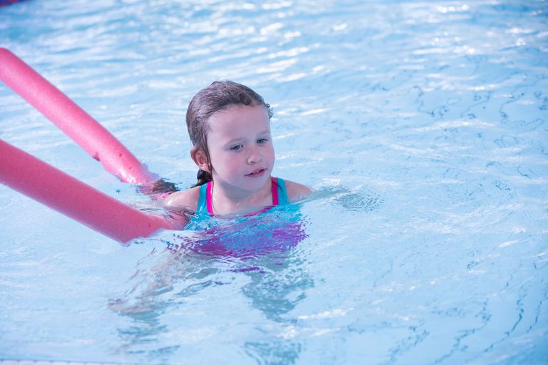Bild på ett barn som simmar med en flytpinne.