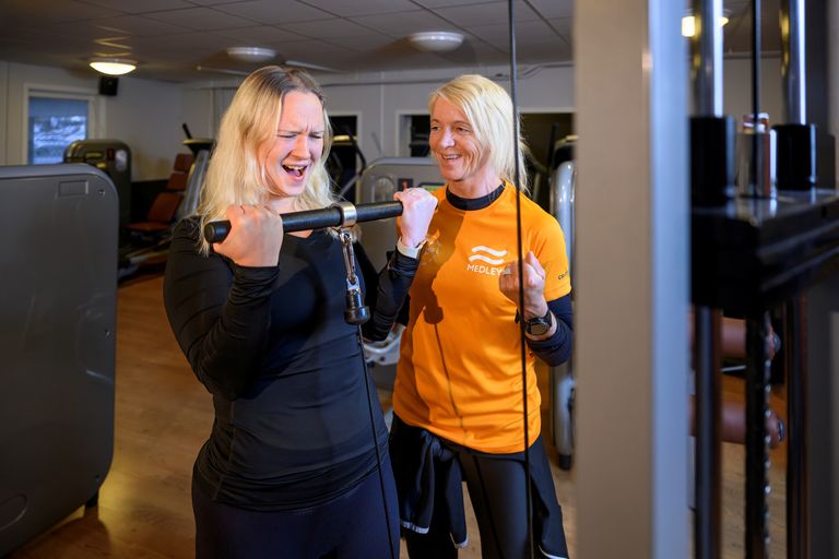 Bild på kvinna som tar i allt vad hon kan när hon får coachning i gymmet av en personlig tränare