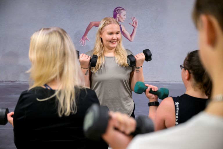 Bild på kvinna som håller i ett gruppträningspass med hantlar