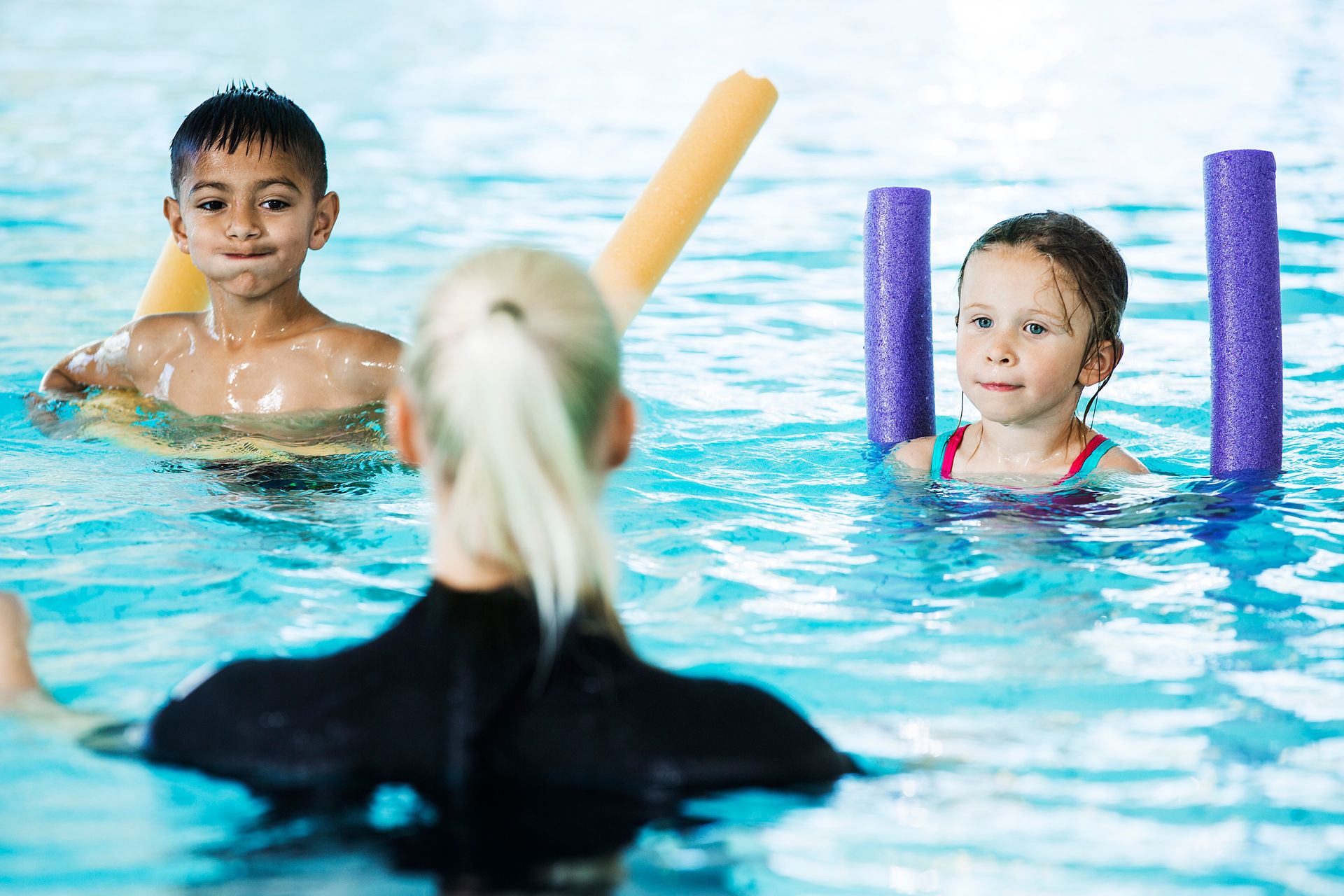 Bild på barn och en siminstruktör i en pool.