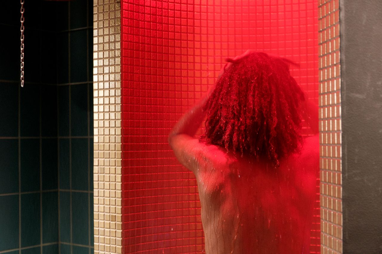 Bild på en person med lockigt hår som duschar i den rödlysande duschen