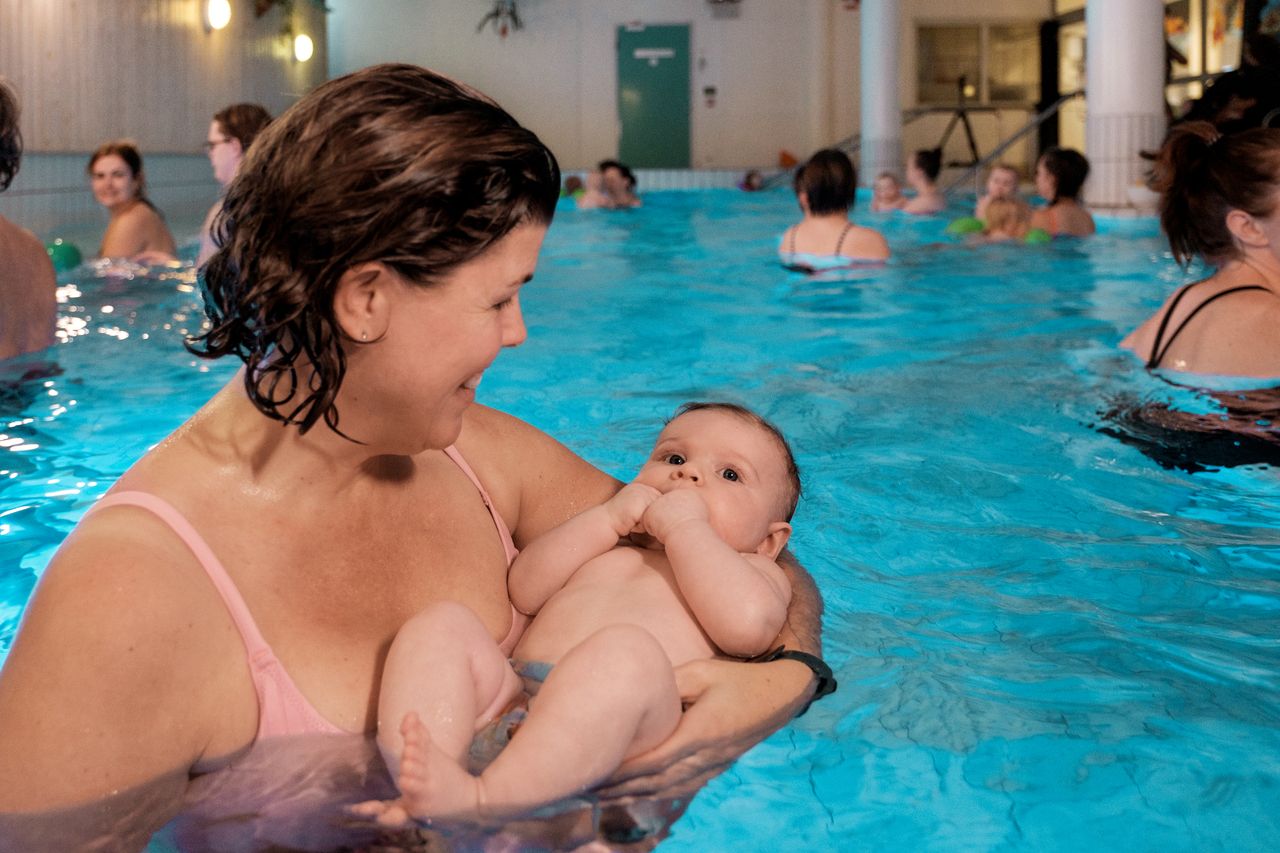 Bild på mamma i vattnet som håller sin bebis i famnen i bassängen