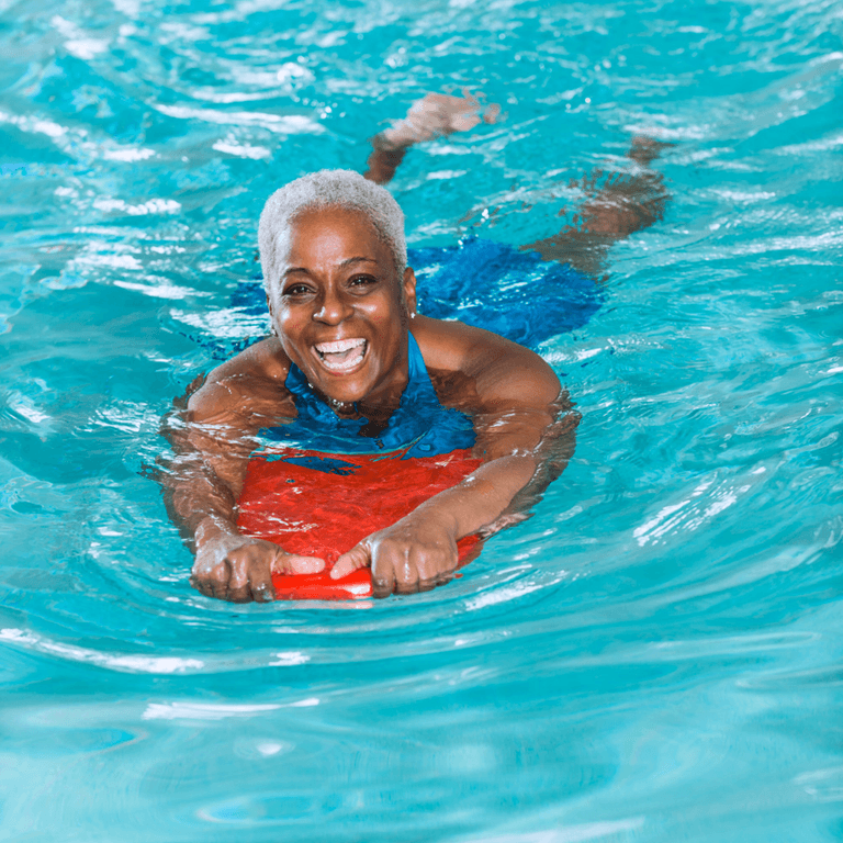 Bild på en kvinna som simmar med ett flytblock.