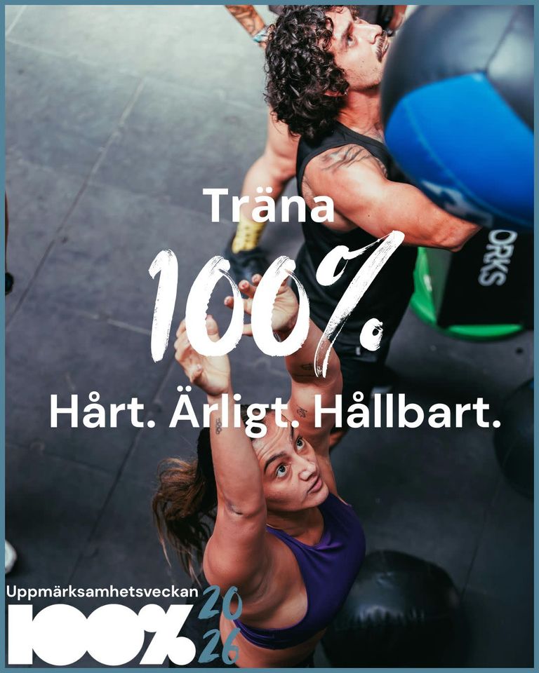 Två personer tränar och sträcker sig upp för att nå en medicinboll som hänger på gymmets vägg. I fet vit svensk text står det: Träna 100 %. Hårt. Ärligt. Hållbart. och Uppmärksamhetsveckan 100 % 2026.
