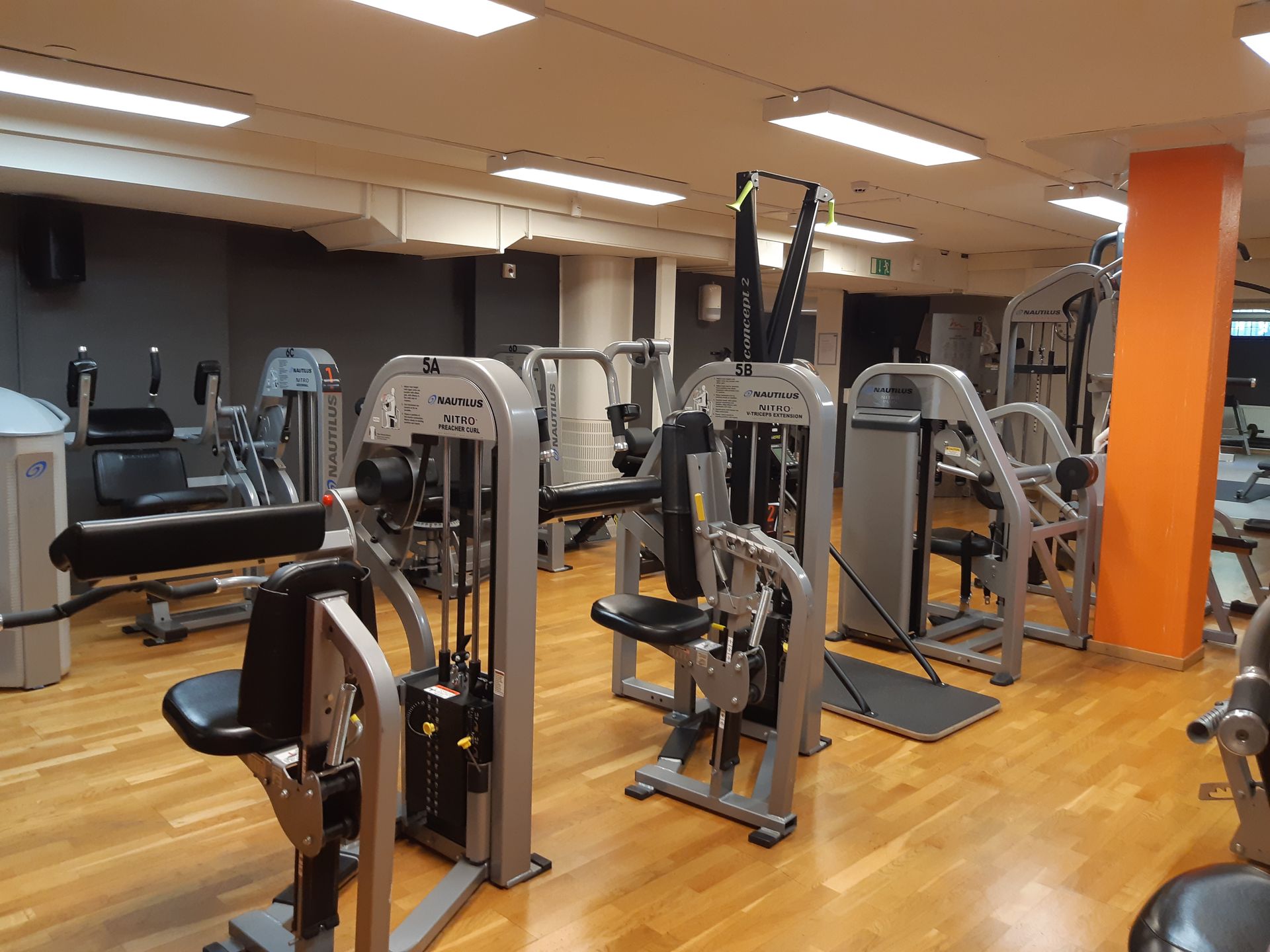 Bild på styrketräningsmaskiner gymmet som har svarta väggar och trägolv
