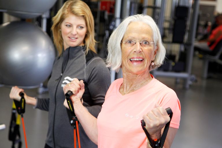 Bild på en äldra kvinna som tränar med en PT i gymmet