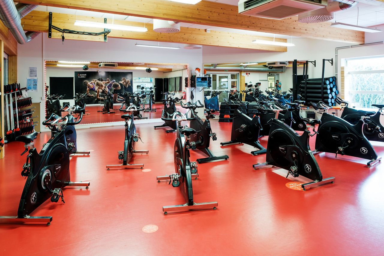 Bild på gruppträningssal med spinningcyklar, golvet är rött och väggarna är täckta med speglar