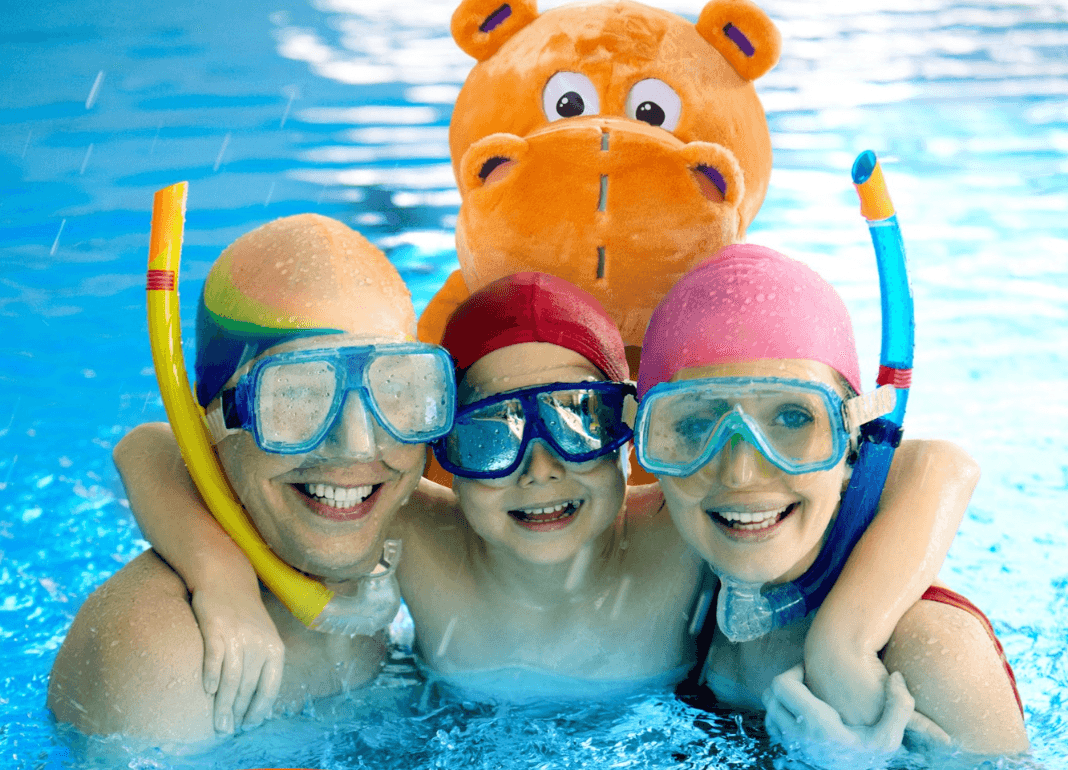 Bild på flodhästen flodis i vattnet med en familj som alla har snorkel på sig