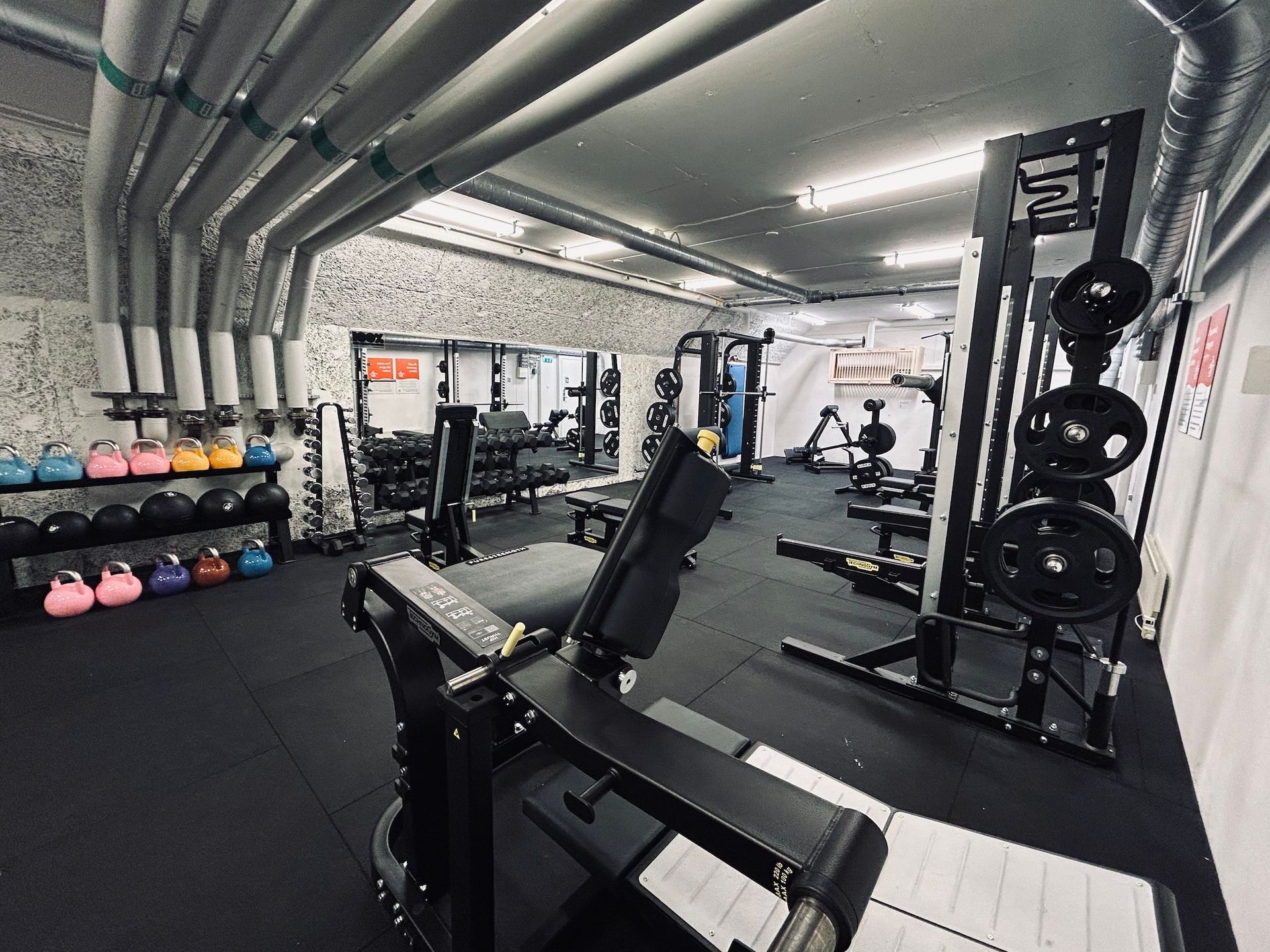 Bild på gymmet som är utan fönster men har spegelvägg och ett stort urval av styrketräningsmaskiner och fria vikter