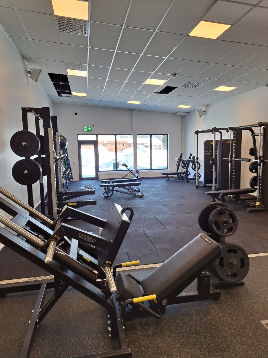 Bild på gym i Älvsbyn med träningsmaskiner såsom skivstång och vikter.
