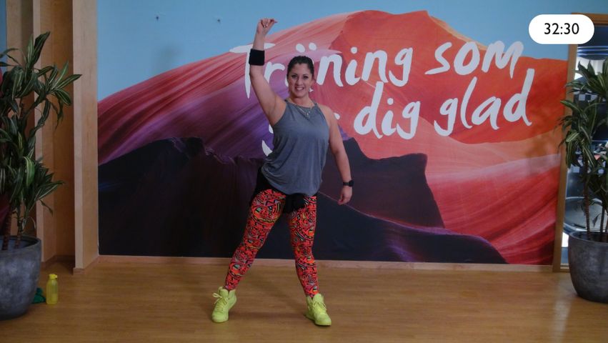 Bild på en kvinna som sträcker upp armen när hon tränar i en gruppträningssal.