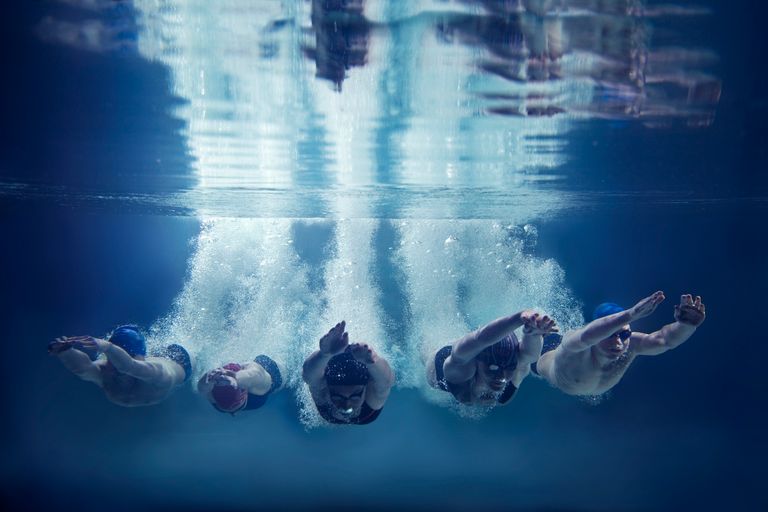 Bild på fyra simmare som dykt ner från kanten och fotas under vattnet